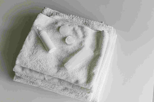clean white folded cotton towels and gentle skincare bottles for a simple daily self-care routine