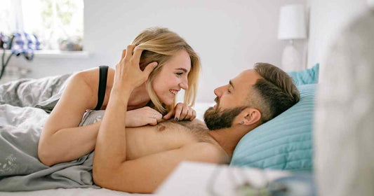 smiling couple embracing comfortably in a bright bedroom representing mutual consent, emotional safety, and healthy intimacy