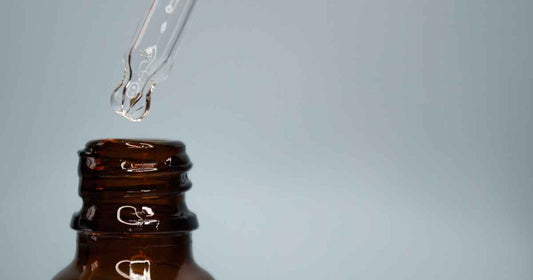 clear water based liquid dripping from glass pipette into amber bottle