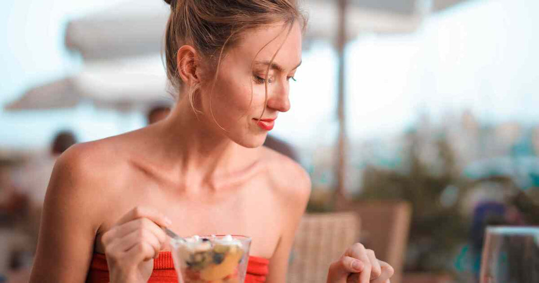 woman enjoying a fresh fruit and yogurt bowl in natural sunlight representing healthy daily nutrition and intimate wellness