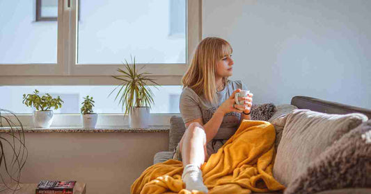 woman relaxing on cozy sofa holding mug reflecting personal contentment and comfort