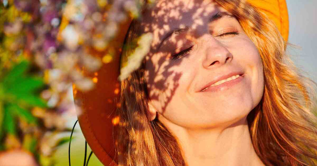 woman closing her eyes peacefully in warm outdoor sunlight representing stress relief, mental calm, and intimate health balance