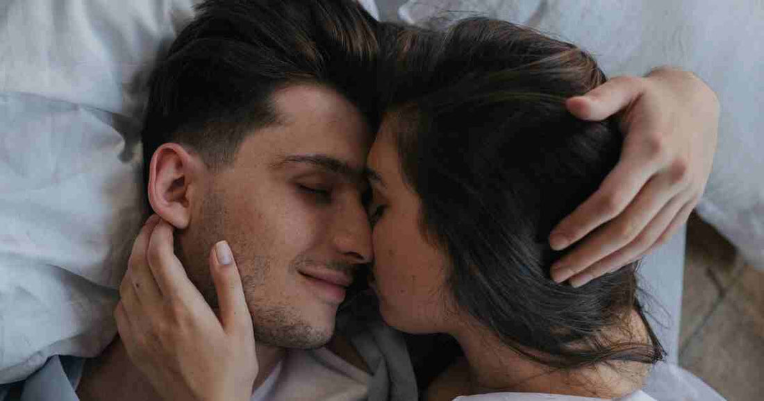 young couple resting tenderly together in bed with gentle touch representing low pressure intimate connection and emotional closeness