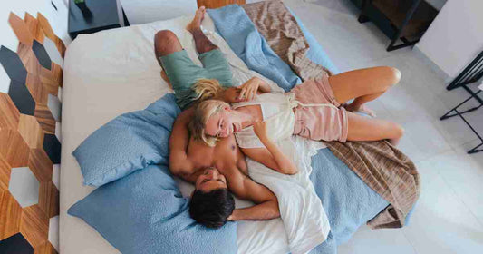 happy couple relaxing and laughing in bed together representing honest intimate communication and emotional security