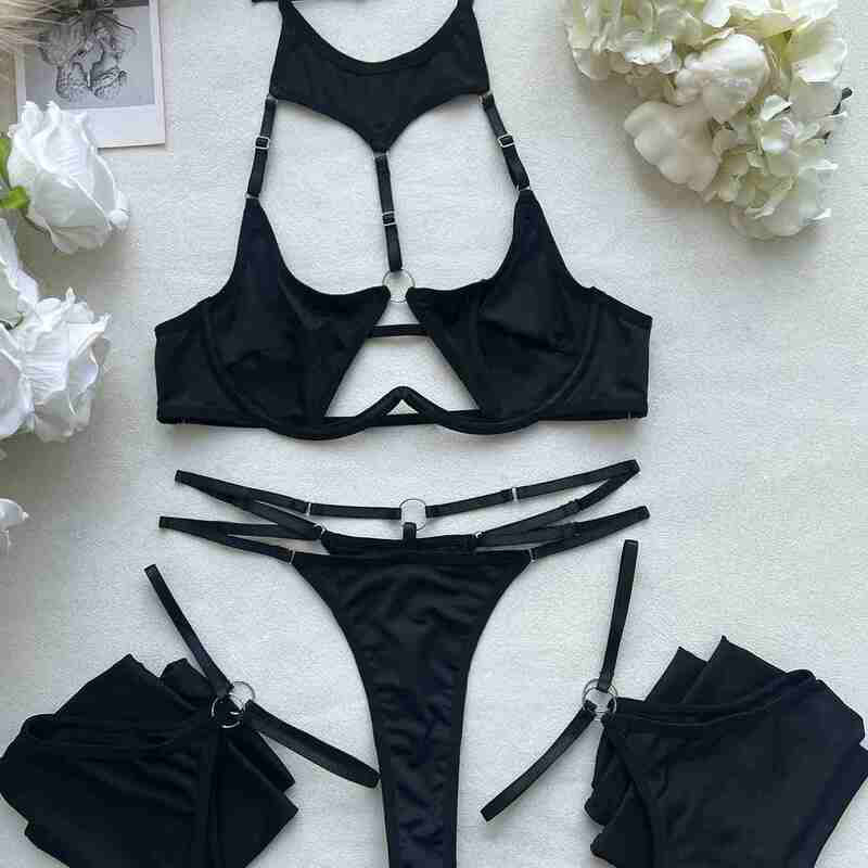 flat lay arrangement of black strappy lingerie set with halter bra, strappy thong, and garter stockings