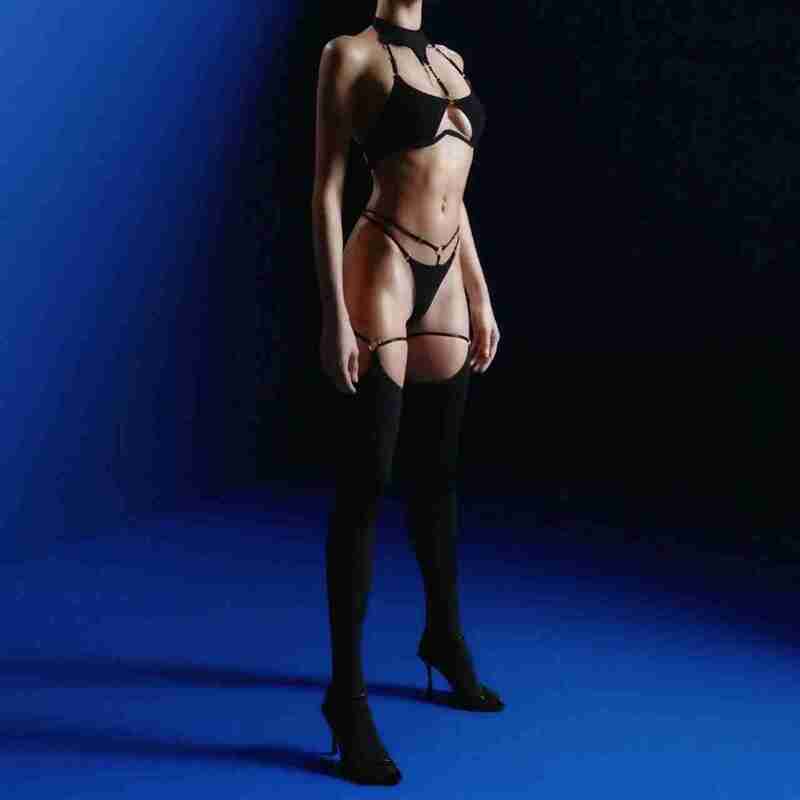 full-length studio view of model wearing black cage lingerie set with garter straps and knee-high stockings